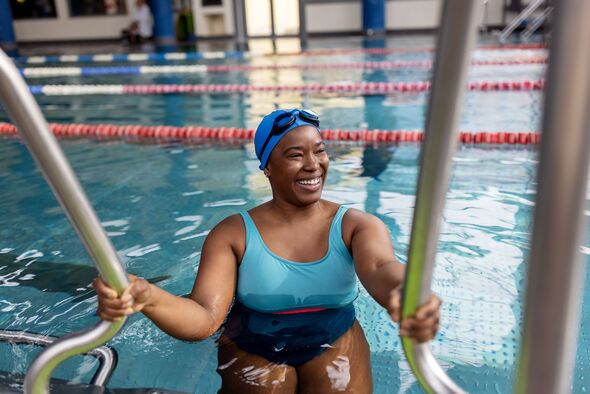 Smiling female swimmer entering the pool Smiling female swimmer entering the pool